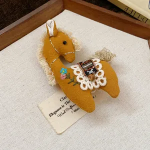 Handmade yellow fabric horse brooch with delicate flower embroidery and lace detail.