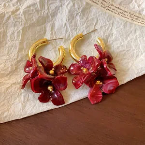 Detail view of red marbled acrylic flower earrings with golden hoop and vintage texture