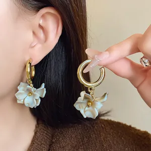 Detailed view of elegant white acrylic marbled flower earrings with gold hoop closures