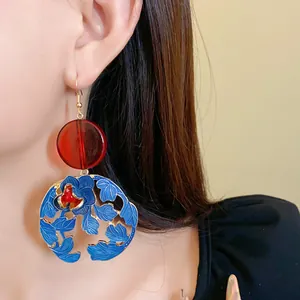 Detail of Chinese style floral earring with red resin bead and blue enamel