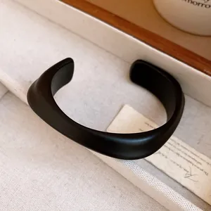 Detailed macro view of the matte black acrylic cuff bracelet with a modern curved design