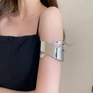 Macro detail of a silver criss-cross geometric metal arm cuff bracelet worn on model's arm