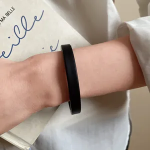 Close-up of a minimalist matte black acrylic bangle bracelet worn on a wrist
