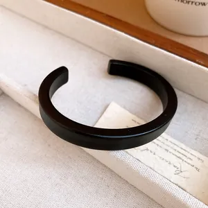 Close-up of minimalist matte black acrylic open bangle bracelet in elegant setting