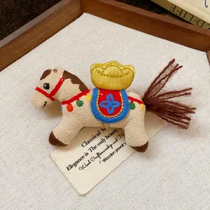 Detailed macro view of an embroidered fabric horse brooch with a golden ingot motif.