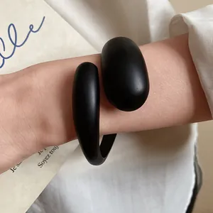 Close-up of minimalist black matte acrylic open bangle worn on wrist