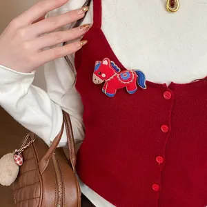 Detail view of a cute red embroidered fabric horse brooch pinned on a red vest.