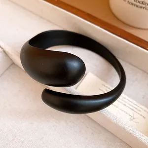 Macro view of the smooth matte texture of the black acrylic open bangle bracelet