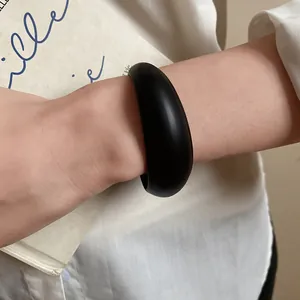 Detail view of a minimalist black acrylic open bangle on a wrist for elegant styling.