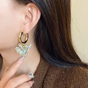 Close-up of French retro acrylic marbled flower hoop earrings worn on model's ear.