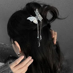Détail d'une pince à cheveux papillon argentée avec strass et longs glands.