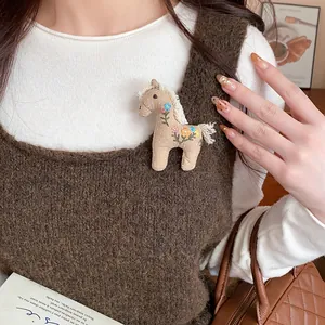 Close-up of cute embroidered fabric horse brooch pinned on a brown knitted sweater