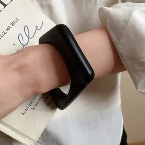 Detailed close-up of a stylish minimalist chunky matte black acrylic bangle for women