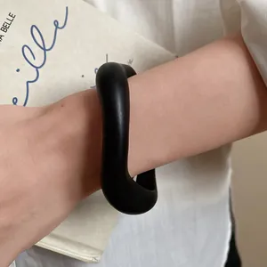 Detailed close-up of a matte black acrylic wavy bangle worn for a minimalist aesthetic