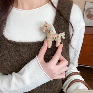 Detailed view of a handmade fabric horse brooch with colorful floral embroidery
