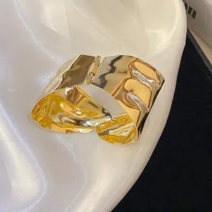 Close-up of a high-quality gold irregular wrinkled metal cuff bracelet with hinge detail