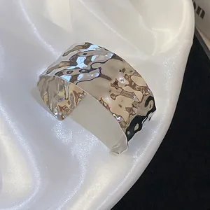 Macro view of the shiny silver crumpled metallic cuff bracelet with irregular texture.