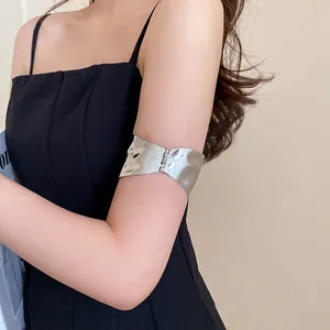 Detail view of irregular pleated metallic arm cuff on upper arm