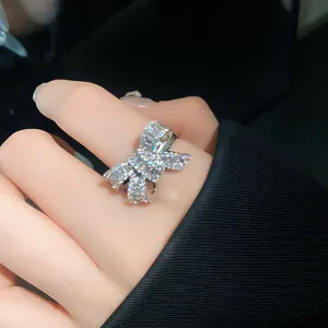 Detailed close-up view of a sparkling silver bow-shaped zircon open ring worn on a finger.