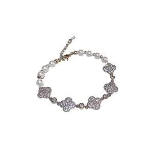 Elegant silver-tone bracelet featuring white pearls and sparkling zircon four-leaf flower charms.