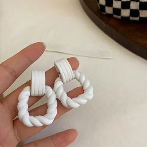 Elegante weiße, gedrehte geometrische Creolen im Vintage-Stil für Damenmode in der Hand