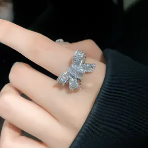 Detailed view of an elegant silver-tone bow ring with pave-set zircons on a finger