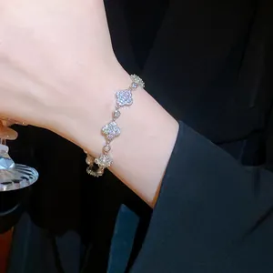 Elegant silver clover charm bracelet with sparkling zircons and pearl details on wrist