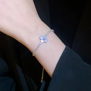Close-up detail of silver-tone four-leaf flower bracelet with sparkling zircons on wrist