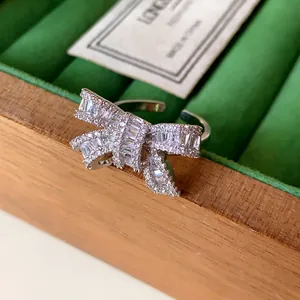 Close-up of elegant silver bow ring with shimmering cubic zirconia stones on green velvet.