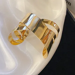 Detailed close-up of shiny gold irregular geometric cuff bracelet on elegant white silk cloth