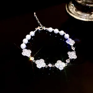Detailed shot of pearl and sparkling zircon four-leaf clover bracelet on dark surface