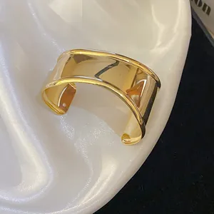 Detailed macro shot of a polished gold-finish wide cuff bracelet with minimalist design
