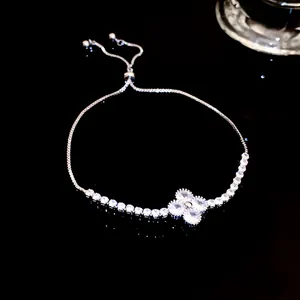 Detailed view of a silver adjustable bracelet with a sparkling clover charm on black.