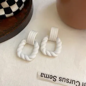Nahaufnahme der weißen, gedrehten geometrischen Ohrringe mit mattem Vintage-Finish
