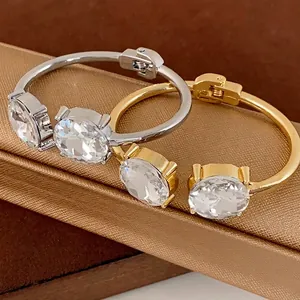 Elegant open bangle bracelets featuring large round clear crystals in gold and silver.