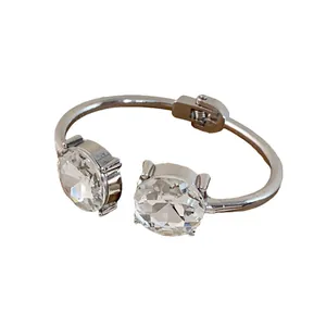Silver cuff bracelet featuring two large round clear faceted crystals on a white background