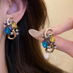 Vintage court style gold earrings with blue and yellow crystals in a twisted S-shape