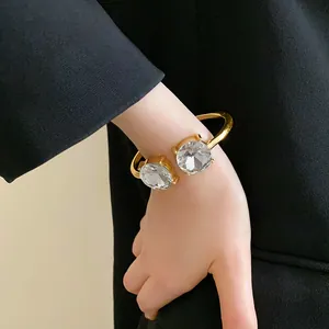 Detail showing a gold open cuff bracelet with sparkling round crystals on the wrist