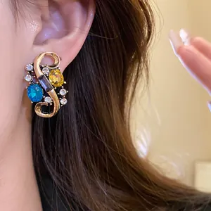 Detailed view of a vintage S-shaped gold earring featuring vibrant colorful rhinestones
