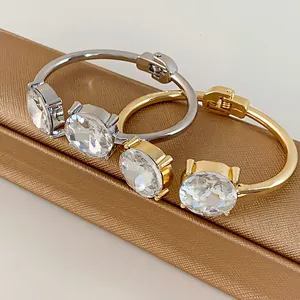 Close-up of elegant silver and gold open bangles set with large round faceted crystals.