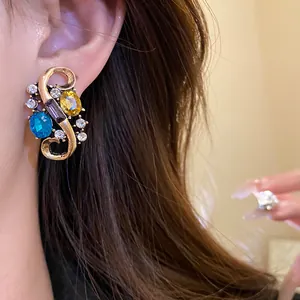 Close-up macro view of vintage palace style S-shaped gold earrings with colorful gemstones
