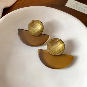 Primo piano dettagliato di orecchini geometrici vintage in resina con accenti dorati