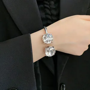 Close-up view of a luxury open cuff bracelet featuring two large brilliant-cut crystals