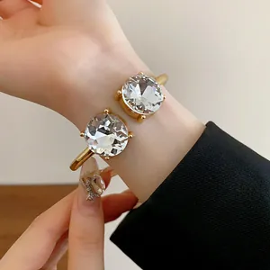 Detail shot of an elegant gold open cuff bracelet featuring two large round crystals.