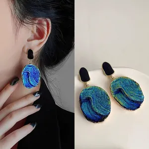 Detail showing the shimmering blue texture and irregular shape of fashion earrings.