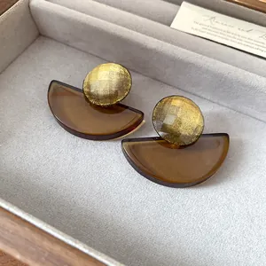 Dettaglio di orecchini vintage in resina ambrata in una scatola portagioie