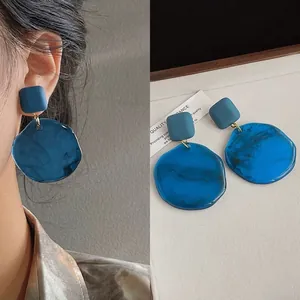 Detail view of blue irregular geometric stud earrings with matte and marble textures.