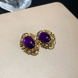 Close-up of French vintage gold ear clips with oval purple stones and pearls