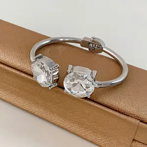 Detail view of a silver-toned open bangle featuring two large faceted round crystals