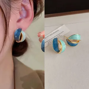 Close-up macro detail of blue and teal enamel pleated fan-shaped stud earrings with gold edges